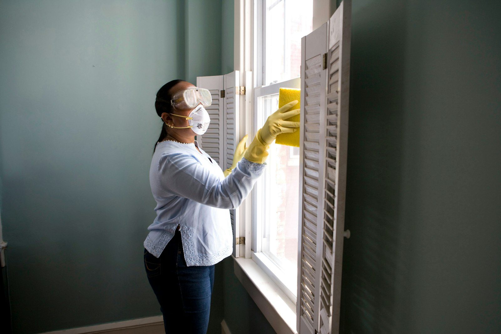 Petugas cleaning service sedang membersihkan jendela